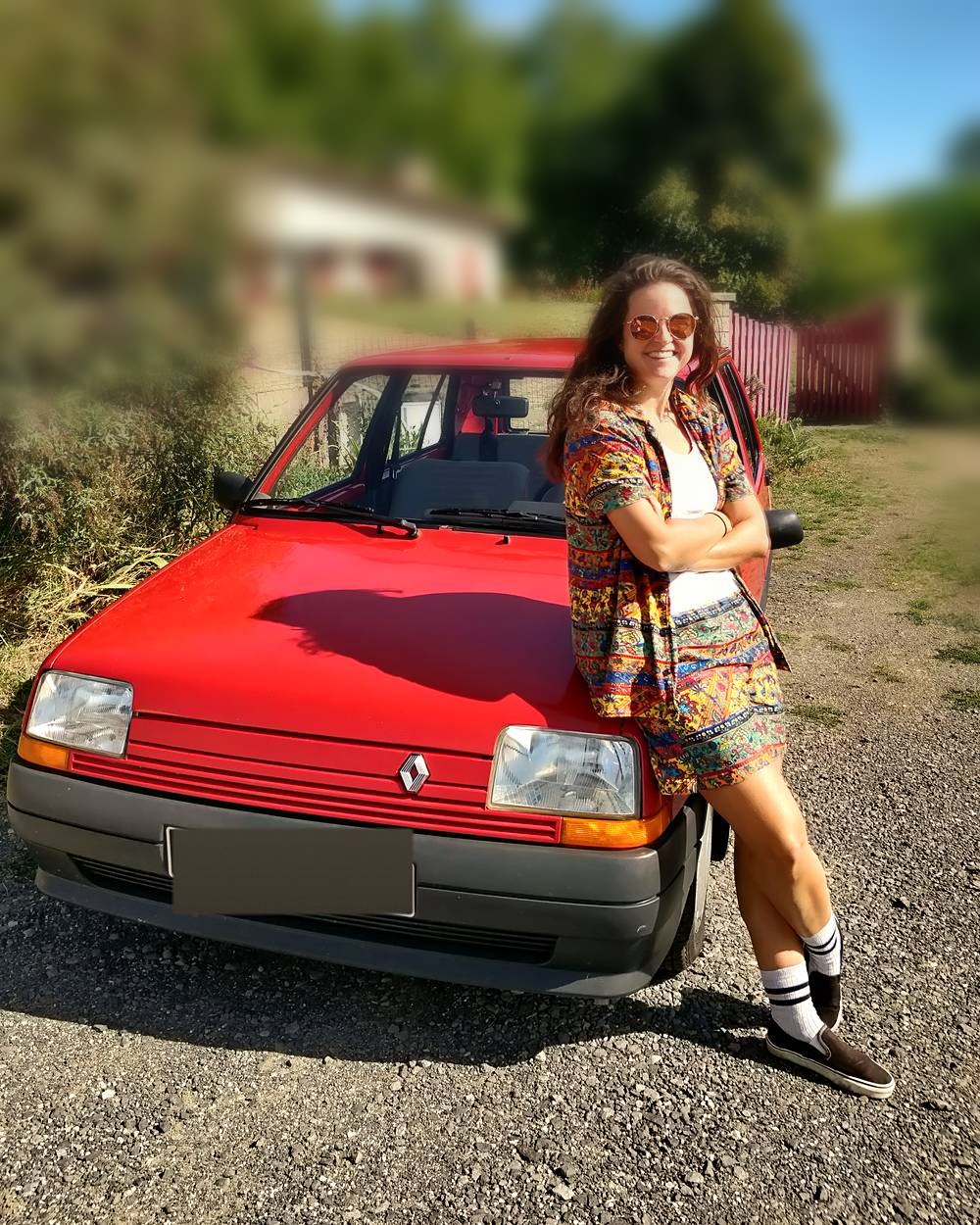 Photo : Audrey en lunettes de soleil, adossée à la Super 5 rouge, au soleil